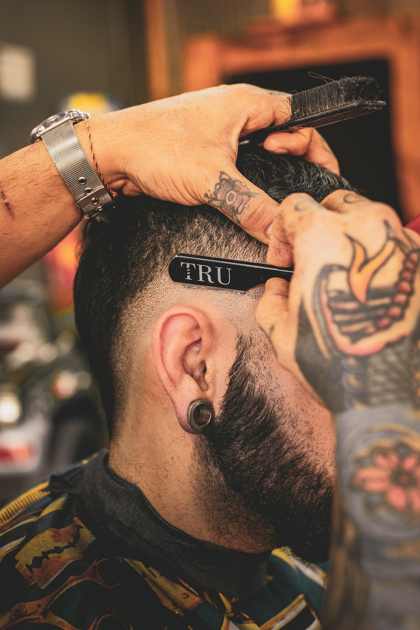 A barber shaping a beard line with a straight razor
