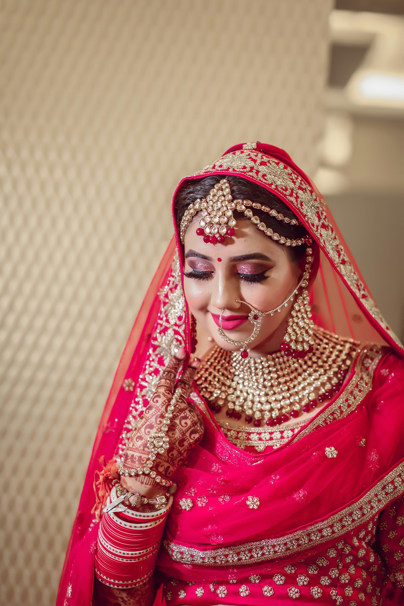 A bride in red and gold, hair and makeup finished