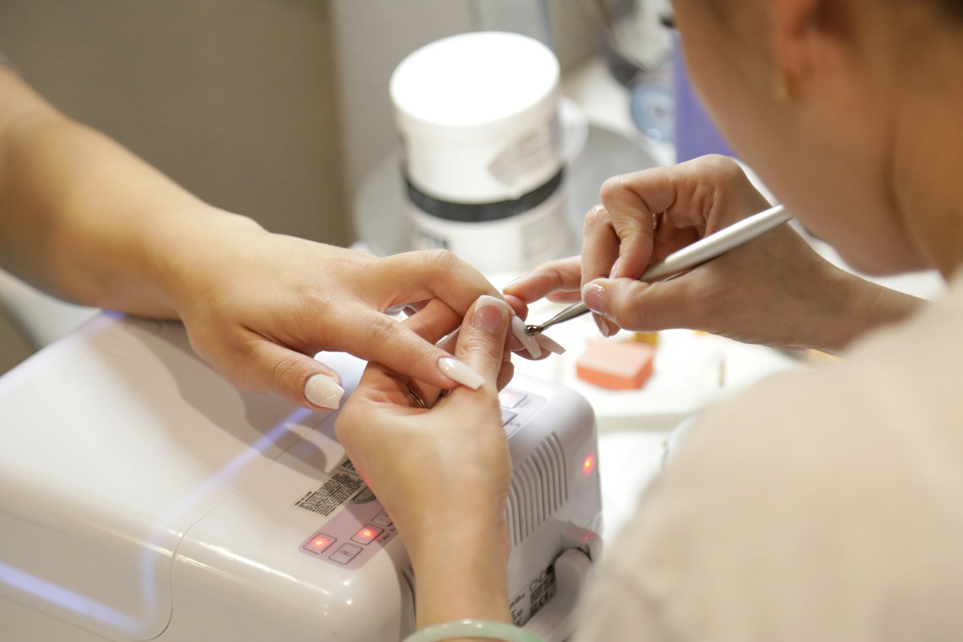 A nail technician shaping and finishing a client's nails