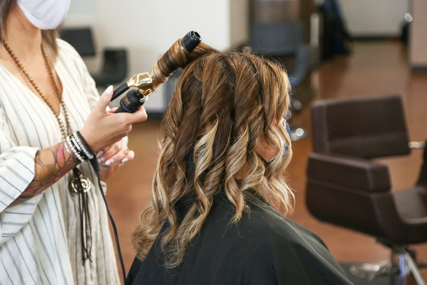 Curling iron shaping a client's hair into loose curls
