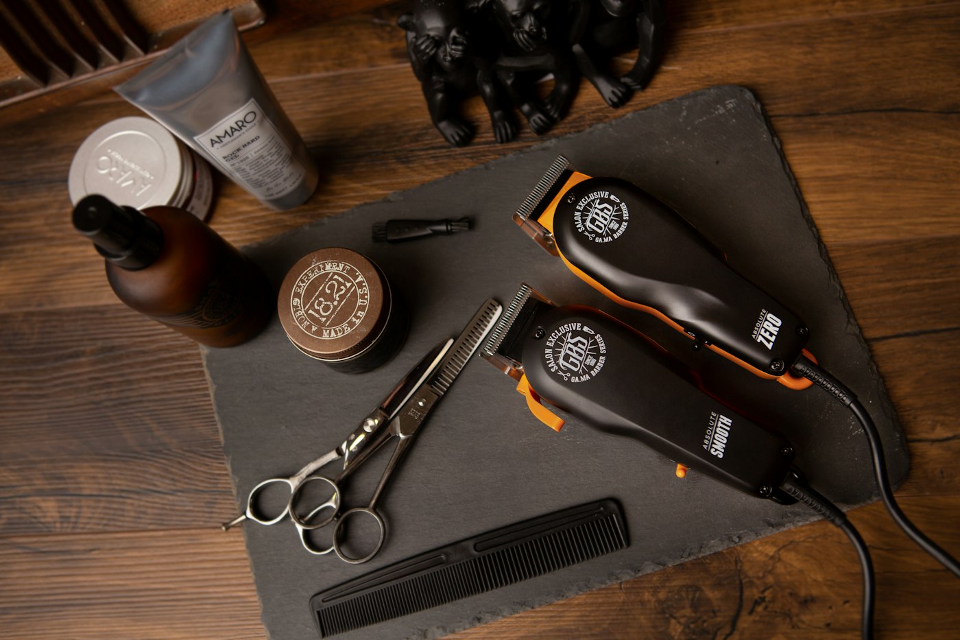 Clippers, shears, comb and grooming products laid out on slate