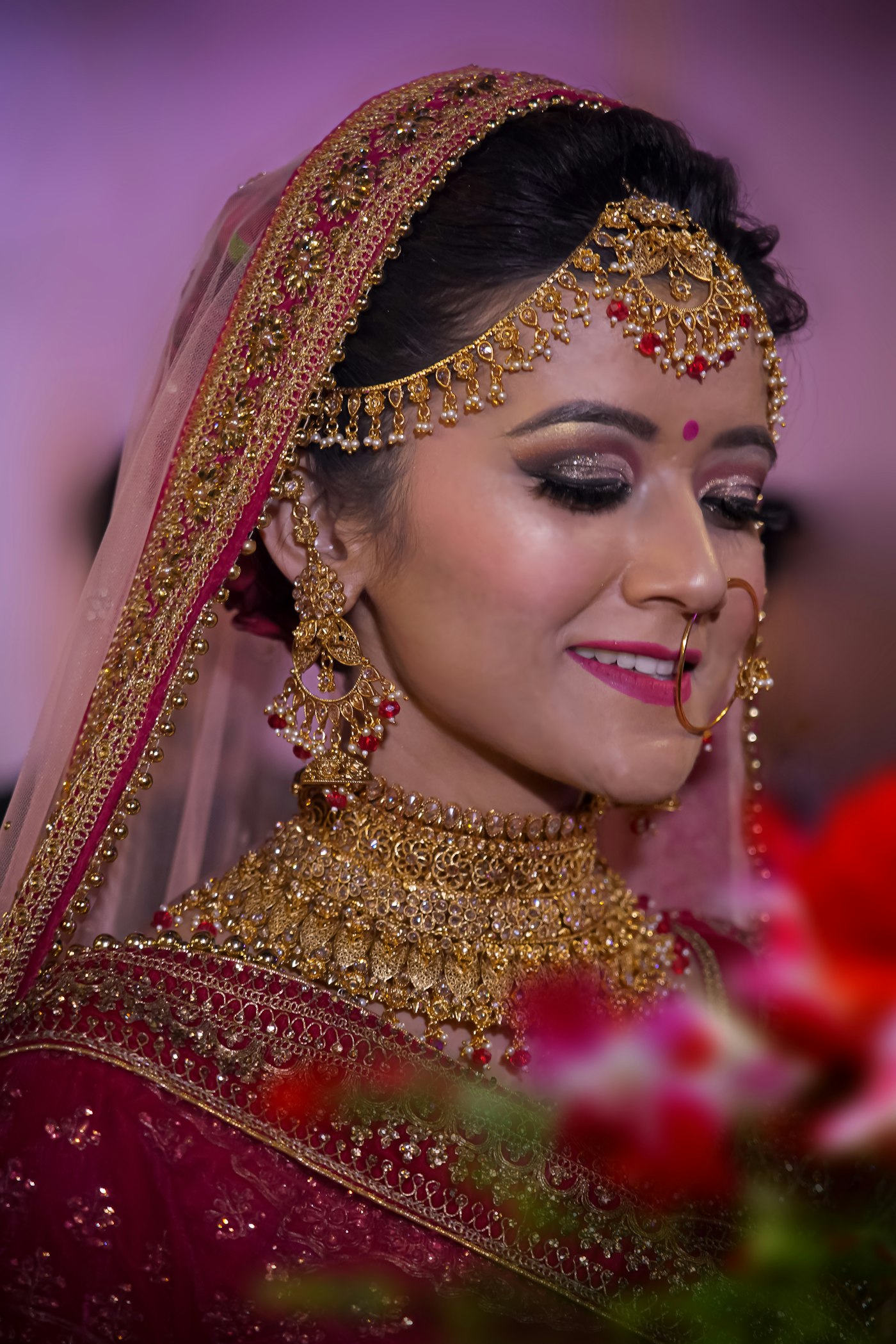 A bride in traditional red and gold with finished hair and makeup